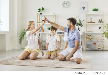 Happy parents making roof with their arms over their son, symbolizing family care and protection. Happy parents making roof with their arms over their son, symbolizing family care and protection. 138694524