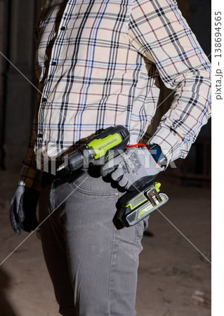 Installer person ready with drill and fasteners on belt 138694565
