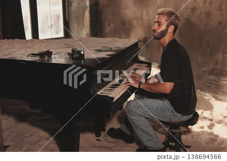 Male piano player preparing for live performance in worn venue Male piano player preparing for live performance in worn venue 138694566