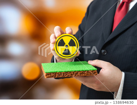 An official holds a radiation symbol over a plot of land. Radioactive contamination and exclusion zones restrict use. Environmental safety defines land suitability and long term risk. An official holds a radiation symbol over a plot of land. Radioactive contamination and exclusion zones restrict use. Environmental safety defines land suitability and long term risk. 138694630