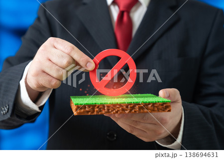 An official holds a no entry sign over a plot of land. Construction permits and restrictions apply. Protected areas and regulations limit development and preserve natural resources. 138694631