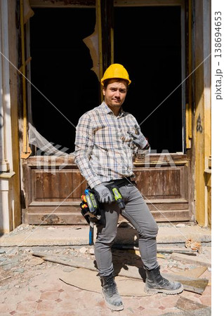Builder in doorway surrounded by debris under restoration work Builder in doorway surrounded by debris under restoration work 138694653
