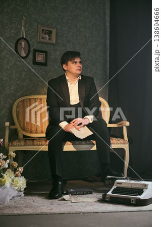 Actor in suit rehearsing with classic typewriter and floral decor Actor in suit rehearsing with classic typewriter and floral decor 138694666