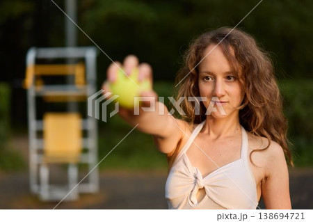 Caucasian woman fitness influencer offering ball in park Caucasian woman fitness influencer offering ball in park 138694721