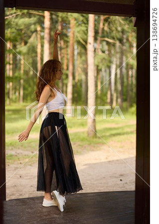 Caucasian woman spinning in casual attire among pine trees 138694726