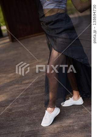 Soft shadowed silhouette of model in sheer skirt and sneakers beside door 138694730