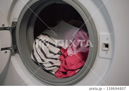 open washing machine full of colorful clothes with color catcher sheet for laundry protection open washing machine full of colorful clothes with color catcher sheet for laundry protection 138694807