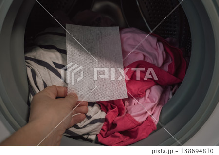 laundry risk concept: color catcher sheet inside washer with mixed brightly colored garments for protection laundry risk concept: color catcher sheet inside washer with mixed brightly colored garments for protection 138694810
