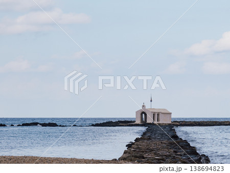 Picturesque seclusion: the whitewashed chapel on a narrow rock jetty extending into the Aegean 138694823