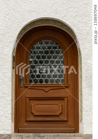 Arched wooden door with circular glass block window Arched wooden door with circular glass block window 138697049