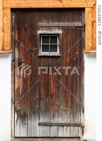 Rustic weathered wooden door with small window 138697052