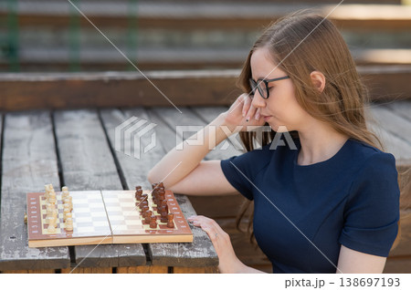 Caucasian woman playing chess outdoors. Caucasian woman playing chess outdoors. 138697193