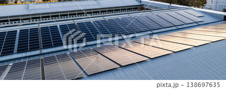 Sustainable power is generated by extensive rooftop photovoltaic systems blanketing industrial city architecture under a warm evening glow. Sustainable power is generated by extensive rooftop photovoltaic systems blanketing industrial city architecture under a warm evening glow. 138697635