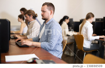 Portrait of concentrated man during lesson in computer room of school computer class Portrait of concentrated man during lesson in computer room of school computer class 138698509