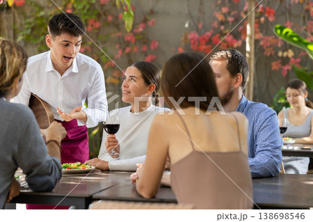 Waiter talking to restaurant guests - taking orders for food and drinks Waiter talking to restaurant guests - taking orders for food and drinks 138698546