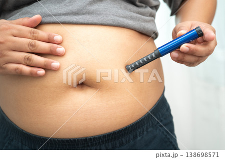 Asian woman injecting herself diabetes injecting insulin in stomach at home. 138698571