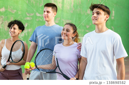 Happy frontenis players with rackets and balls standing in open court Happy frontenis players with rackets and balls standing in open court 138698582
