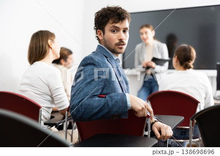 Young smiling man attending lecture in university Young smiling man attending lecture in university 138698696