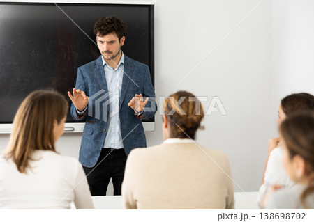Young male professor explaining subject to classroom full of students Young male professor explaining subject to classroom full of students 138698702