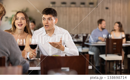 Couple and adult man eating and talking in restaurant Couple and adult man eating and talking in restaurant 138698714