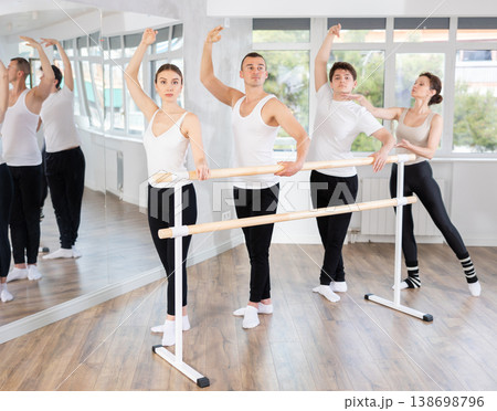 Group of ballet enthusiasts practicing at barre with experienced ballerina 138698796