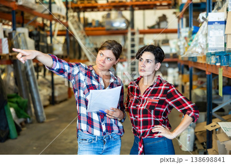 Woman manager discussing order list with female worker at warehouse of building materials 138698841