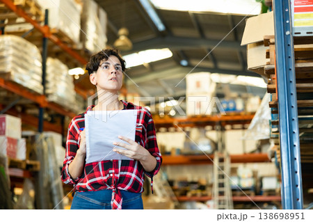 Woman inspecting warehouse to check quantity of goods on shelves Woman inspecting warehouse to check quantity of goods on shelves 138698951