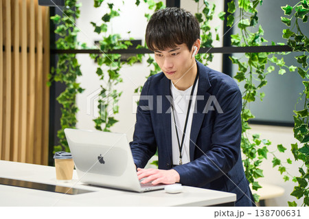 緑のあるオフィスでスタンディングデスクでPC作業に集中する外資系の若手男性SE 緑のあるオフィスでスタンディングデスクでPC作業に集中する外資系の若手男性SE 138700631
