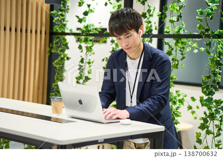 緑のあるオフィスでスタンディングデスクでPC作業に集中する外資系の若手男性SE 緑のあるオフィスでスタンディングデスクでPC作業に集中する外資系の若手男性SE 138700632