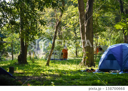 Forest tents, hanging robes and shaded paths create a clear retreat backdrop. The natural scene suits meditation and religion content. 138700668