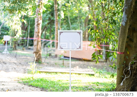 An ornamental frame on a slim stand sits under warm light. The empty center leaves room for formal outdoor notice text. An ornamental frame on a slim stand sits under warm light. The empty center leaves room for formal outdoor notice text. 138700673