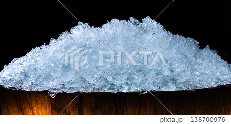 Pile of crushed ice cubes in wood bucket on dark background with copy space. Crushed ice cubes foreground for beverages, beer, whisky, fruit juice, milk, fresh food or fresh vegetables. 138700976