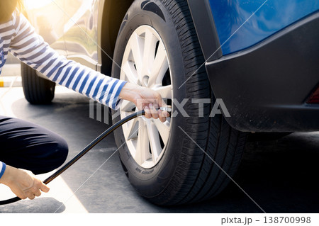 Woman inflates the tire. Woman checking tire pressure and pumping air into the tire of car wheel. Car maintenance service for safety before travel. Tire inflating point. Filling air in the tyre of car Woman inflates the tire. Woman checking tire pressure and pumping air into the tire of car wheel. Car maintenance service for safety before travel. Tire inflating point. Filling air in the tyre of car 138700998