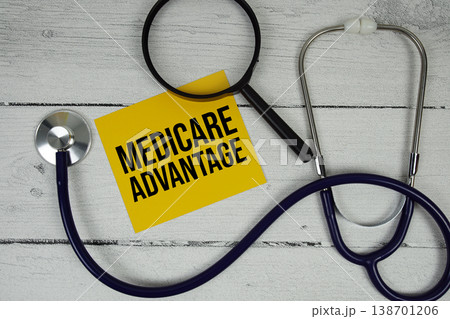 Medicare Advantage text with Magnifying glass and Medical Stethoscope on wooden background 138701206