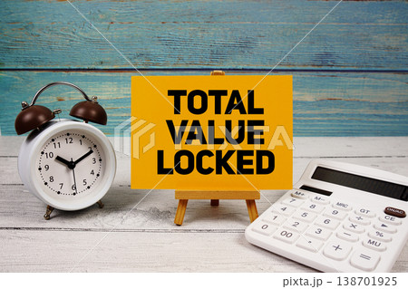 Total Value Locked text written on paper card with calculator and alarm clock on wooden background 138701925