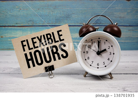 Flexible Hours text written on paper card with alarm clock on wooden background Flexible Hours text written on paper card with alarm clock on wooden background 138701935