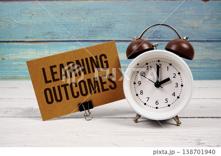 Learning Outcomes text written on paper card with alarm clock on wooden background 138701940