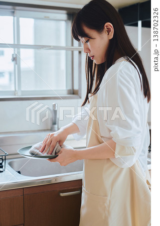 キッチンで食器を洗う女性 日常の家事や丁寧な暮らしを表現した生活シーン 138702326