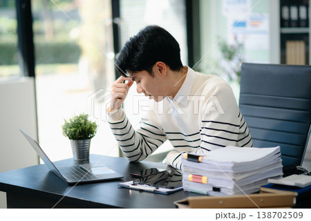 Overworked young Asian businessman office worker suffering from neck pain after had a long day at her office desk. 138702509