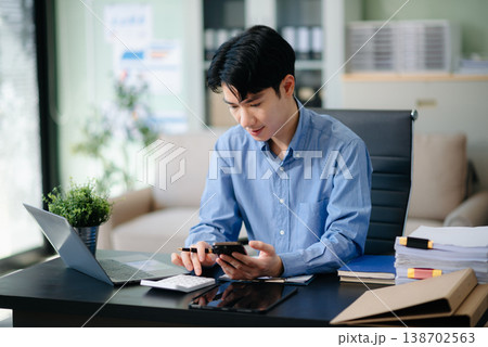 Confident Asian businessman typing laptop computer and digital tablet at office Confident Asian businessman typing laptop computer and digital tablet at office 138702563