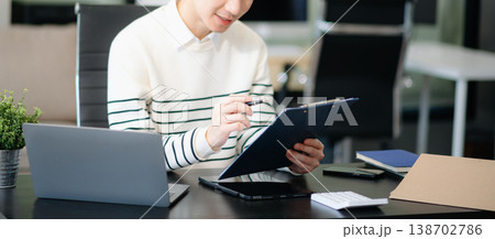 Young handsome man typing on tablet and laptop while sitting at the working table Young handsome man typing on tablet and laptop while sitting at the working table 138702786