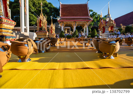 Dozens of covered alms bowls sit spaced across a yellow mat. Silver bases and fabric straps show an organized setup. Dozens of covered alms bowls sit spaced across a yellow mat. Silver bases and fabric straps show an organized setup. 138702799