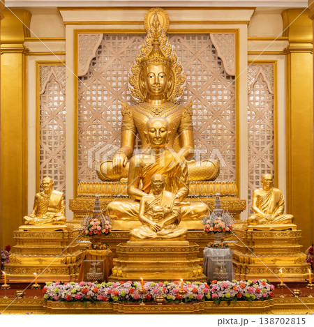 A golden Buddha shrine fills the hall with seated statues and flower rows. Chandeliers and columns frame the symmetrical altar. A golden Buddha shrine fills the hall with seated statues and flower rows. Chandeliers and columns frame the symmetrical altar. 138702815
