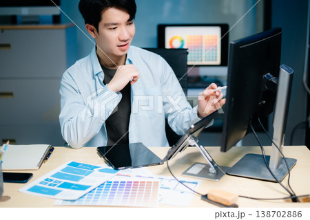 Asian UX,UI designer reviewing app wireframes and color samples in modern office. Creative process, web design 138702886