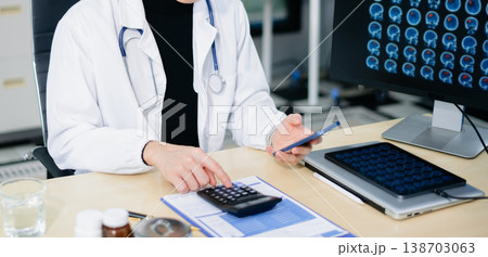 Asian doctor studying brain MRI scans on monitor and writing notes in modern clinic. Concept of radiology, neurology Asian doctor studying brain MRI scans on monitor and writing notes in modern clinic. Concept of radiology, neurology 138703063