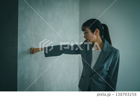 暗い表情で壁に拳を突き出す会社員 暗い表情で壁に拳を突き出す会社員 138703258