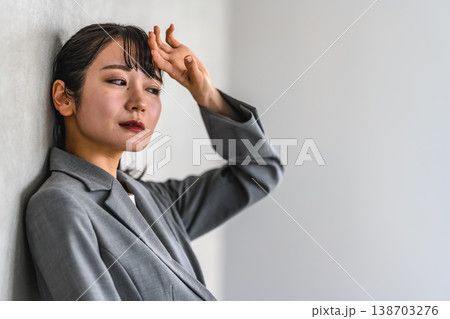 壁にもたれ、額に手を当てる女性 138703276