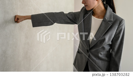 壁に拳を当てて苦悩するビジネスウーマン 138703282