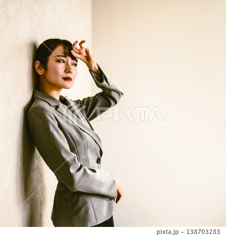 悩むビジネスウーマン、壁にもたれる 138703283