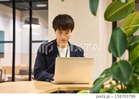 外資系IT企業のオフィスで、観葉植物の近くでノートパソコンを開き作業する若い男性 外資系IT企業のオフィスで、観葉植物の近くでノートパソコンを開き作業する若い男性 138703790